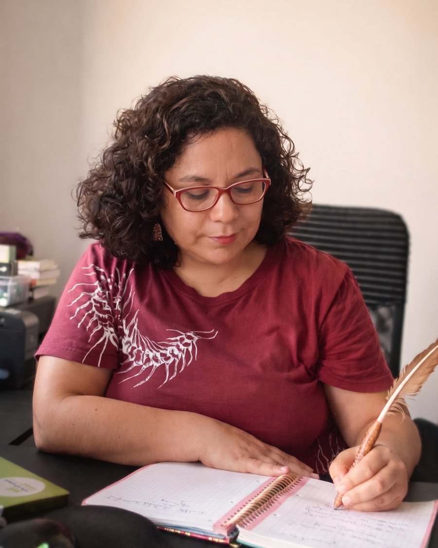 Johanna Luzmira Soto Bustos escribiendo con pluma en su cuaderno de notas de sesión.